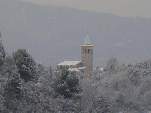 a building with a steeple on a hill with trees at Agriturismo Istrice Innamorato in Campello sul Clitunno