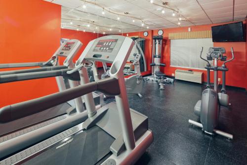 a gym with several tread machines and orange walls at Country Inn & Suites by Radisson, Clinton, IA in Clinton