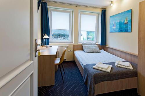 a hotel room with a bed and a desk and two windows at Olkuska 107 A in Gdynia