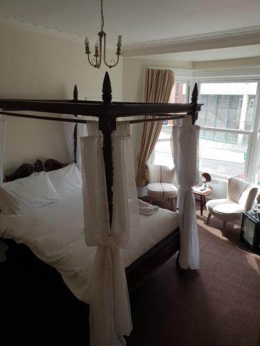a bedroom with a bed with white sheets and curtains at The Camberley in Harrogate