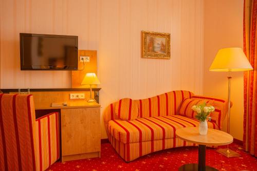 a living room with a couch and a tv at Alte Landratsvilla Hotel Bender in Westerburg