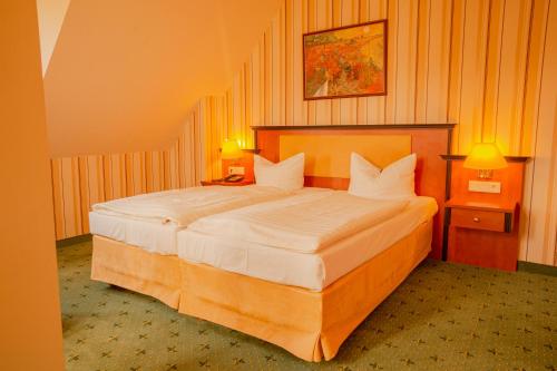 a bedroom with a large bed with two night stands and two lamps at Alte Landratsvilla Hotel Bender in Westerburg