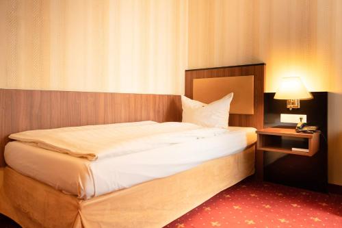 a bedroom with a bed and a lamp and a phone at Alte Landratsvilla Hotel Bender in Westerburg
