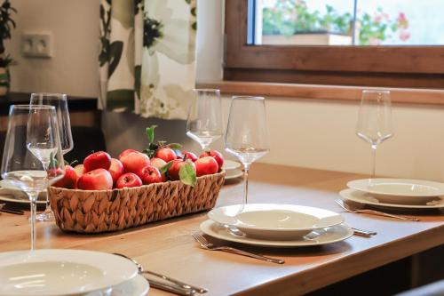 a table with plates and glasses and a basket of apples at Klausenstein Gutshof Hollersbach in Hollersbach im Pinzgau