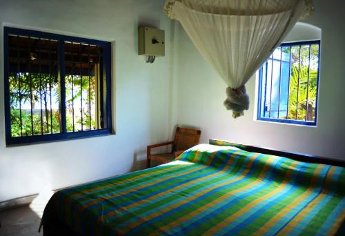 um quarto com uma cama e duas janelas em 15LMD Villa in Front of the Lagoon em Batticaloa