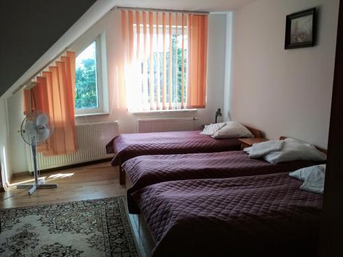 two beds in a room with two windows and a fan at VITA Augustów in Augustów