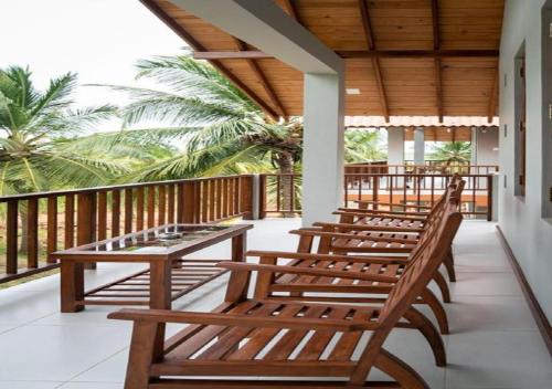a row of wooden benches sitting on a porch at The Coconut Gardens Hotel & Restaurant in Tissamaharama