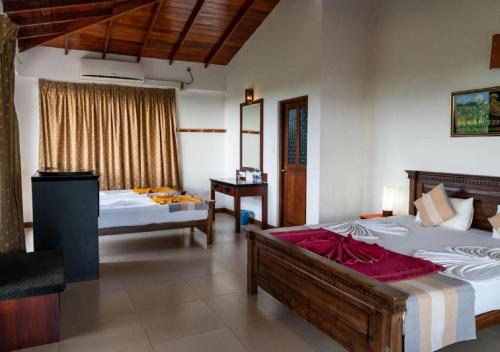 a bedroom with two beds and a desk in it at The Coconut Gardens Hotel & Restaurant in Tissamaharama