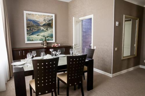 a dining room with a table and chairs and a painting at Hotel Portal in Maykop