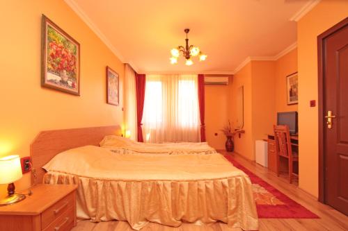 a bedroom with a large bed and a chandelier at Family Hotel Silvestar in Veliko Tŭrnovo