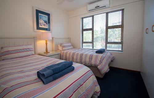 1 dormitorio con 2 camas y ventana en 18 The Shades Umhlanga Rocks, en Durban