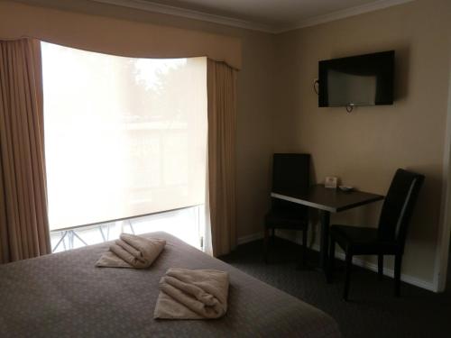 a hotel room with a bed and a desk and a window at Ballarat Central City Motor Inn in Ballarat