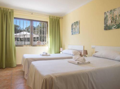two beds in a room with green curtains and a window at Villa Nerea - Plusholidays in Calpe