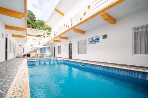 an indoor swimming pool with blue water in a building at OYO Hotel Posada San Vicente, Huatulco in Santa Maria Huatulco