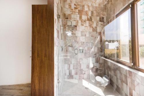 a bathroom with a shower with a stone wall at Azabu Hotel Collection in San Luis Potosí