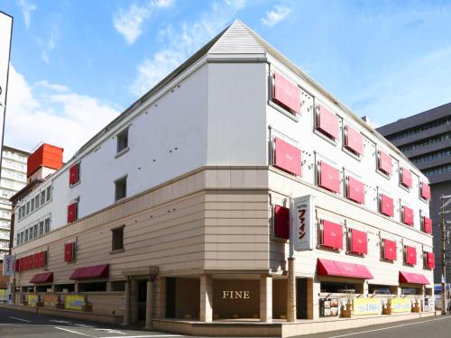 a white building with red windows on a street at Hotel Fine Garden Juso in Osaka