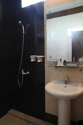a bathroom with a sink and a shower with a mirror at Hotel Roditha Banjarbaru in Banjarbaru