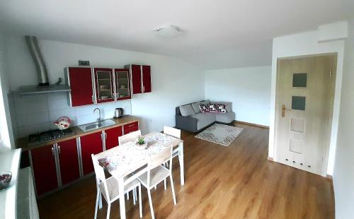 uma sala de estar com uma mesa e uma cozinha com armários vermelhos em U Górala Tadzia em Krynica-Zdrój