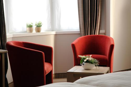two red chairs and a table in a hotel room at Ambassador Hotel in De Panne