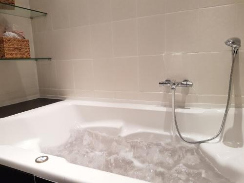 eine mit Wasser bedeckte Badewanne mit Dusche in der Unterkunft Große 130qm Ferienwohnung mit Whirlpool in Sulzbach