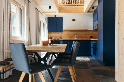 a kitchen with blue cabinets and a wooden table and chairs at Ferienhaus Alpen Lodge und die Gams in Neurur