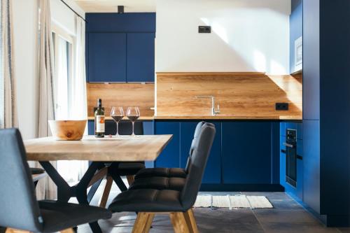 a kitchen with blue cabinets and a wooden table and chairs at Ferienhaus Alpen Lodge und die Gams in Neurur