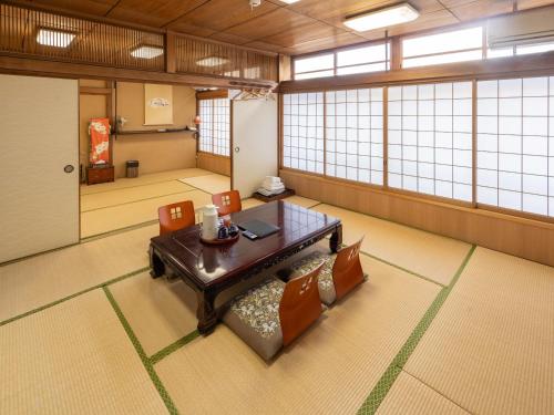 a room with a table and chairs and windows at Fujiya Ryokan in Kyoto