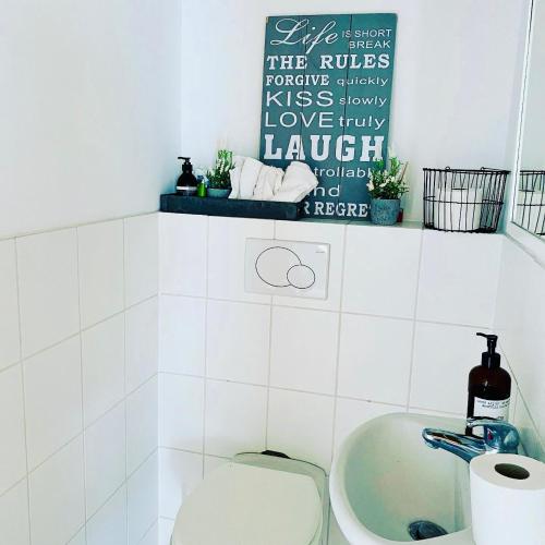 a white bathroom with a toilet and a sink at Ferienhaus No. 4 in Perl