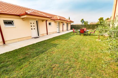 a house with a yard with chairs and a table at Simo apartments airport Podgorica in Podgorica