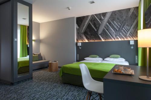 a hotel room with a green bed and a mirror at Villa Park Med. & SPA in Ciechocinek