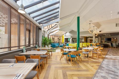 a restaurant with tables and chairs and windows at Holiday Inn Leamington Spa - Warwick, an IHG Hotel in Leamington Spa