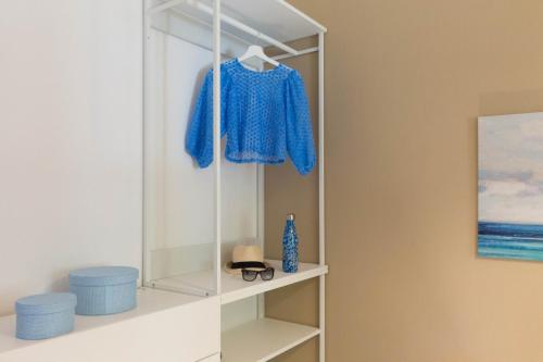 biała półka z niebieską koszulą i kapeluszem w obiekcie Casa Azzurra - Casa con giardino privato a Costa Rei a due passi dal mare w mieście Costa Rei