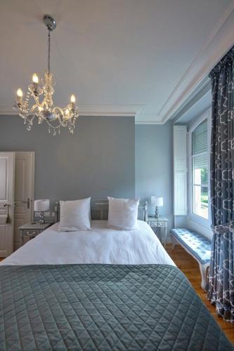 une chambre avec un grand lit et un lustre dans l'établissement Chateau Vary, à Jarzé