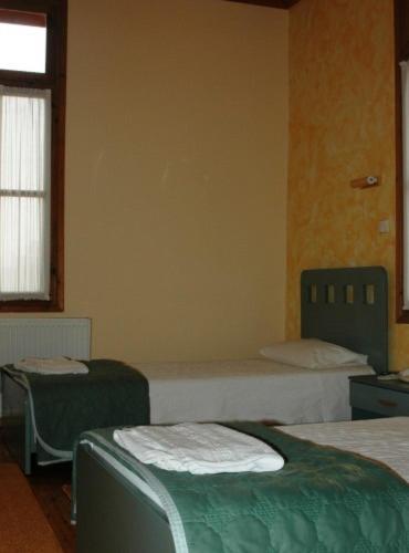 a room with three beds and a window and a room with two beds at Hotel Koukouli in Souflíon