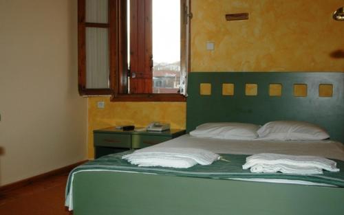 a bedroom with a bed with a green headboard and a window at Hotel Koukouli in Souflíon