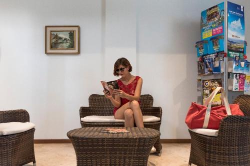 Una donna seduta su una sedia che tiene in braccio un bambino di Hotel Marittima a Rimini