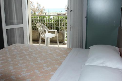 a bedroom with a bed and a balcony with a chair at Hotel Sedonia in Cervia