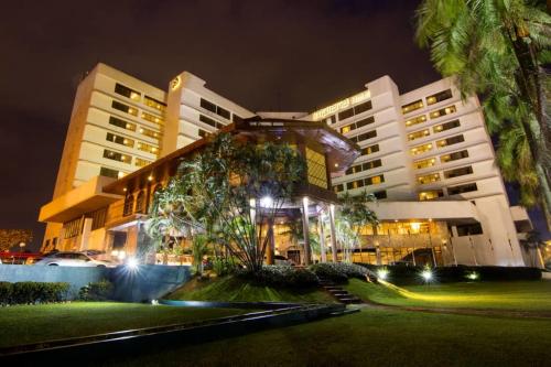 a large building with palm trees in front of it at night at Impiana Hotel Ipoh in Ipoh