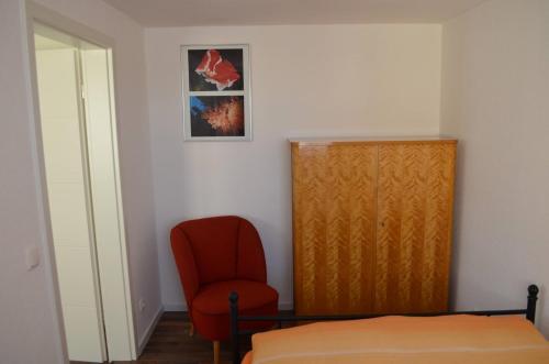 a bedroom with a bed and a red chair at Ferienhaus Köhler in Marienberg