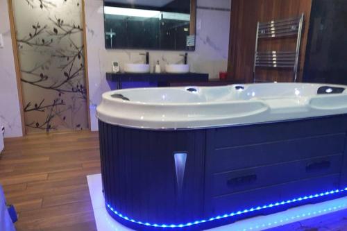 a large bath tub in a bathroom with a mirror at LES CLEFS DU PARADIS avec SPA in Montferrand-le-Château