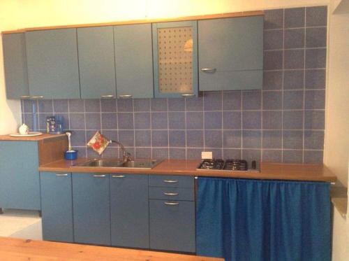 uma cozinha com armários azuis e um lavatório em Casa del Vento em Lipari