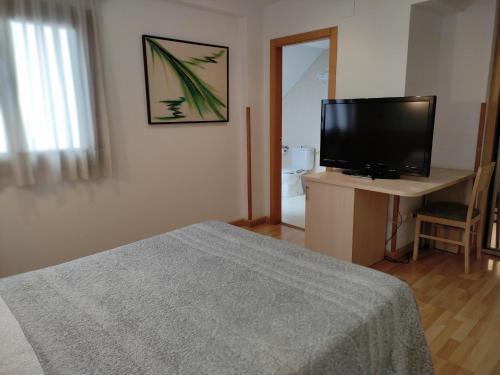 a bedroom with a bed and a television on a desk at Nap Carta Puebla in Oviedo
