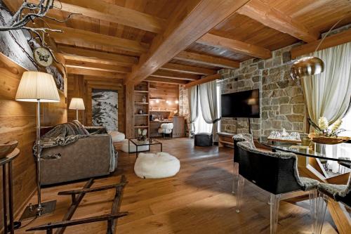 a living room with wooden ceilings and a stone wall at Fiocco di Neve Relais & SPA in Limone Piemonte