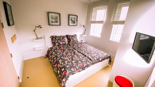 een kleine slaapkamer met een bed en een televisie bij Kaap Hoorn Club Bed en Breakfast in Hoorn