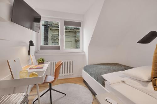 a small white room with a bed and a desk at Beethoven Hotel Dreesen - furnished by BoConcept in Bonn