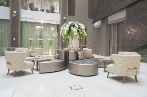 a lobby with chairs and tables and a vase with flowers at The Legacy Luxury Hotel, Algiers in Alger