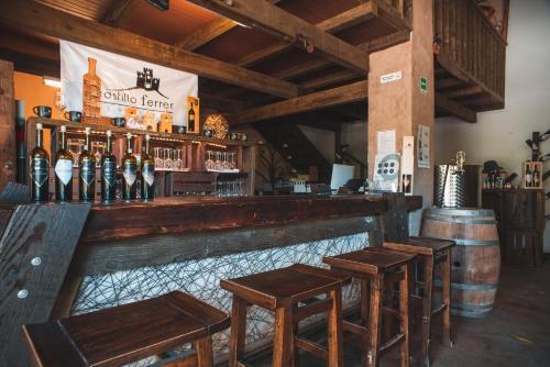 a bar with wooden stools and bottles of wine at Hotel Castillo Ferrer in Valle de Guadalupe