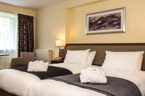 um quarto de hotel com duas camas e uma cadeira em Holiday Inn Norwich North, an IHG Hotel em Norwich