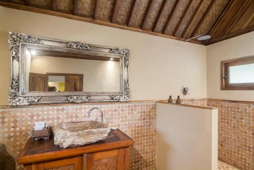 La salle de bains est pourvue d'un miroir et d'une table en bois. dans l'établissement Dolcemare Resort, à Gili Air