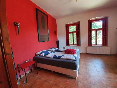 Un dormitorio con una pared roja y una cama. en Vakantiehuis Casa Mama met prive zwembad en Monyoród